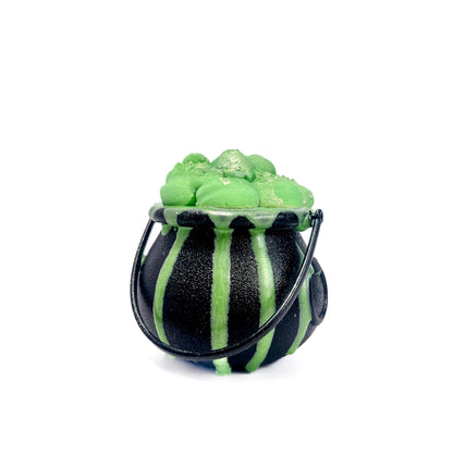 A black cauldron, drizzled with green soap, filled with green bath bomb, and topped with green bubble bar.