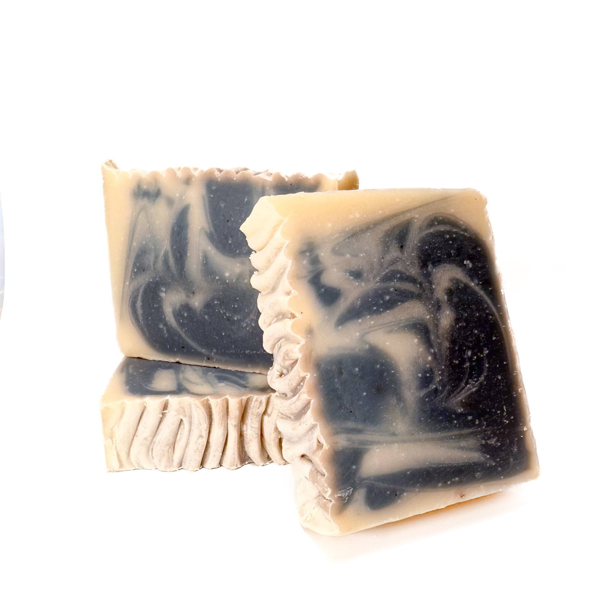 Three handmade bar soaps swirled gray and natural tan. Two are top facing to show texture. 