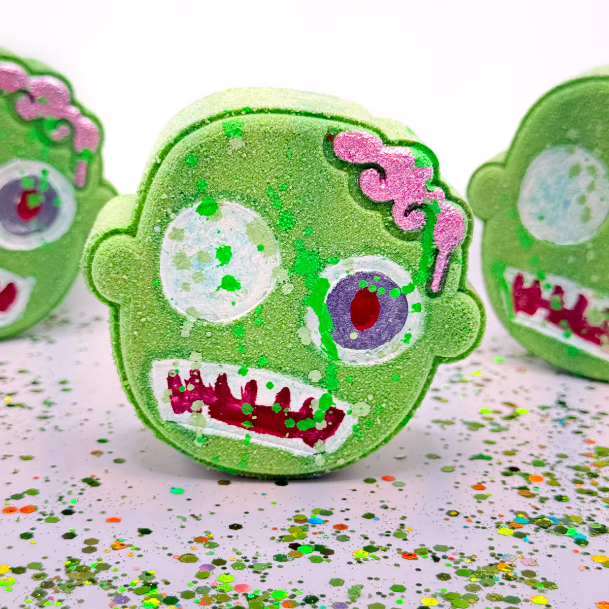 One green and one purple zombie shaped bath bombs. Hand painted with a funky zombie theme with splattered zombie guts! 